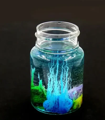 Contenitore di vetro con liquido colorato e reazione luminosa.