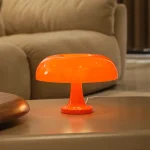 Lampada decorativa in stile futuristico di colore arancione, con forma a fungo, posizionata su un tavolo in un ambiente domestico moderno.