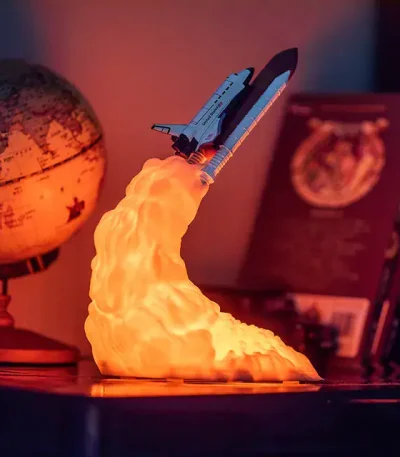 Modello di razzo spaziale in miniatura con fiamma accesa, perfetto come decorazione scientifica o oggetto da collezione.