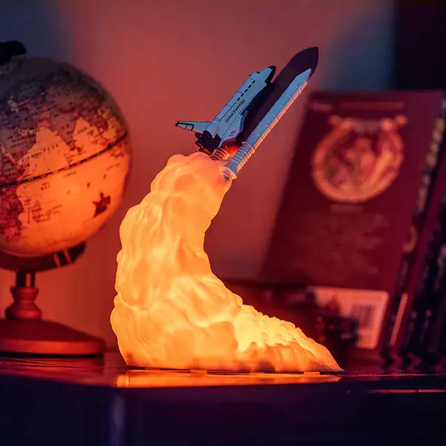 Modello di razzo spaziale in miniatura con fiamma accesa, perfetto come decorazione scientifica o oggetto da collezione.