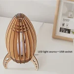 Lampada decorativa a forma di razzo in legno con sorgente LED e porta USB, ideale come oggetto scientifico e decorativo per ambienti moderni e studi.