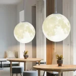 Due lampade a forma di luna, luminose e decorative, pendono dal soffitto in un ambiente moderno, creando un'atmosfera accogliente e originale. Perfette come elementi di design per ambienti interni.