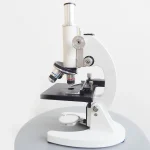 Microscopio da laboratorio bianco con obiettivi e piastra portaoggetti.