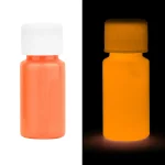 Pillola di vernice fluorescente arancione visibile in luce normale e fluorescente, evidenziando la sua brillantezza sotto luce UV.