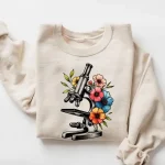 Cartello con microscopio e fiori colorati, ideale per decorazione scientifica o per gli amanti della biologia.