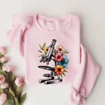 Controlla questa illustrazione di microscopio circondato da fiori colorati, perfetta per una t-shirt originale e scientifica.