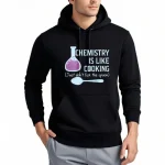Felpa scientifica con iscrizione "La chimica è come cucinare" e illustrazione di un flacone da laboratorio e cucchiaio, perfetta per gli amanti della scienza.