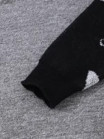 Manica di maglione nero con stampa di elementi scientifici, posata su sfondo grigio. Perfetto per decorazioni e abbigliamento a tema scientifico.