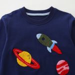 Maglione per bambini con ricamo di razzo e pianeti.
