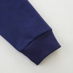Dettaglio di una manica di una maglietta blu navy con polsino a coste, tessuto morbido e di alta qualità, perfetta per un look casual e confortevole.