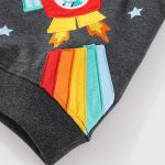 Dettaglio di una giacca con ricamo di un astronauta e arcobaleno, ideale come decorazione scientifica e oggetto di abbigliamento per appassionati di spazio.