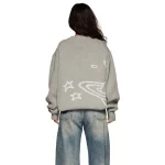 Giacca grigia oversize con motivi di stelle e galassie bianchi, stile casual, vista da dietro.
