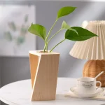 Pianta in vaso di design geometrico in legno naturale, decorazione moderna per interni, ideale per uffici e case, con foglie verdi vivaci.
