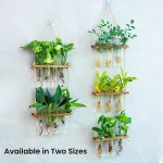 Decorazioni botaniche con vasi sospesi in legno e corda, ideali per interni moderni e naturali, disponibili in due dimensioni.