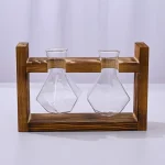 Due beute in vetro con forma conica e base piatta, posizionate su un supporto in legno con struttura rettangolare.